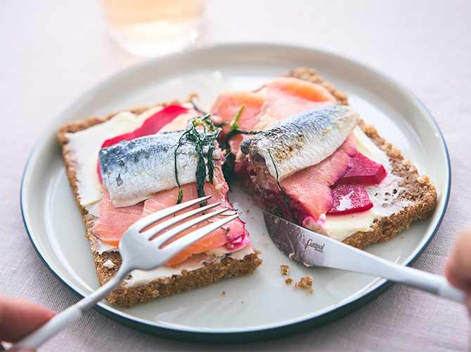 炙ったイワシのマリネとスモークサーモンをビーツコンフィ、ハーブとともに、ほのかな酸味が特徴的なライ麦パンに乗せて、ナイフとフォークでお召し上がりいただく「スモークサーモンとイワシのスモーブロー(オープンサンド)」。