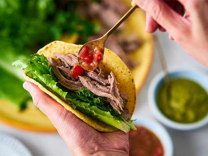 ほぐしたカルニータス(豚肩ロースのコンフィ)を、葉野菜と一緒にトルティーヤで包んで、2種類のソースで味わう「2色のサルサで味わうカルニータスのタコス」。